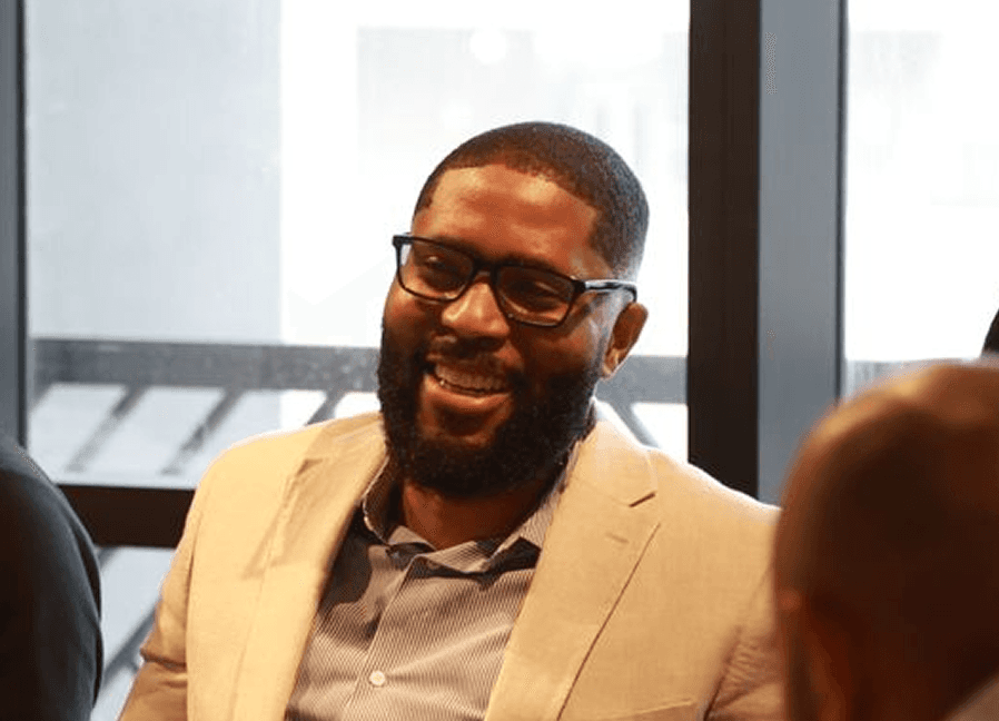 Two colleagues smiling while working together on a laptop.