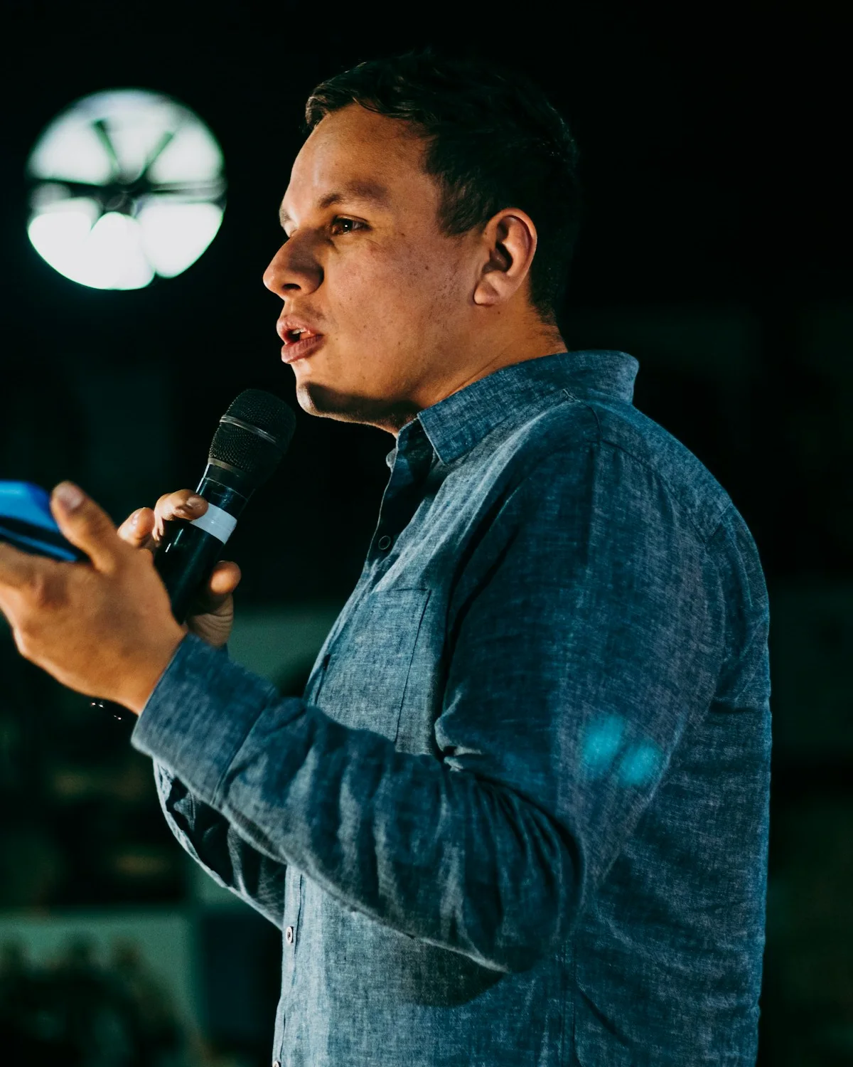 Caleb Moreno in a denim shirt, speaking into a microphone