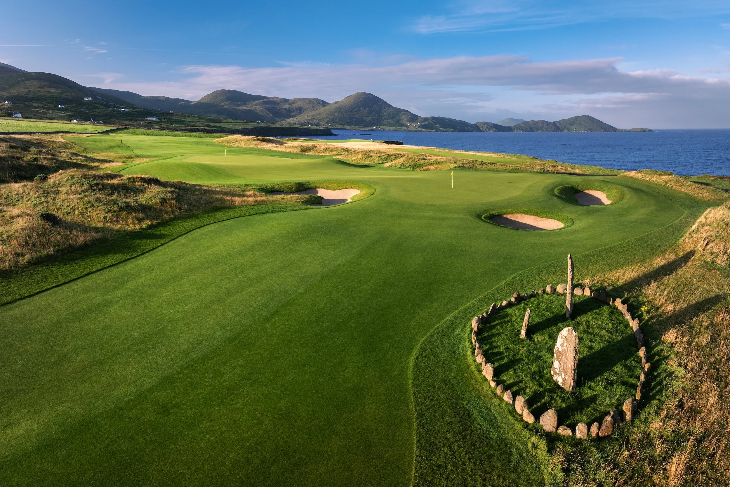 A green at Hog's Head golf links, with an ancient stone circle beside the fairway and the coast beyond