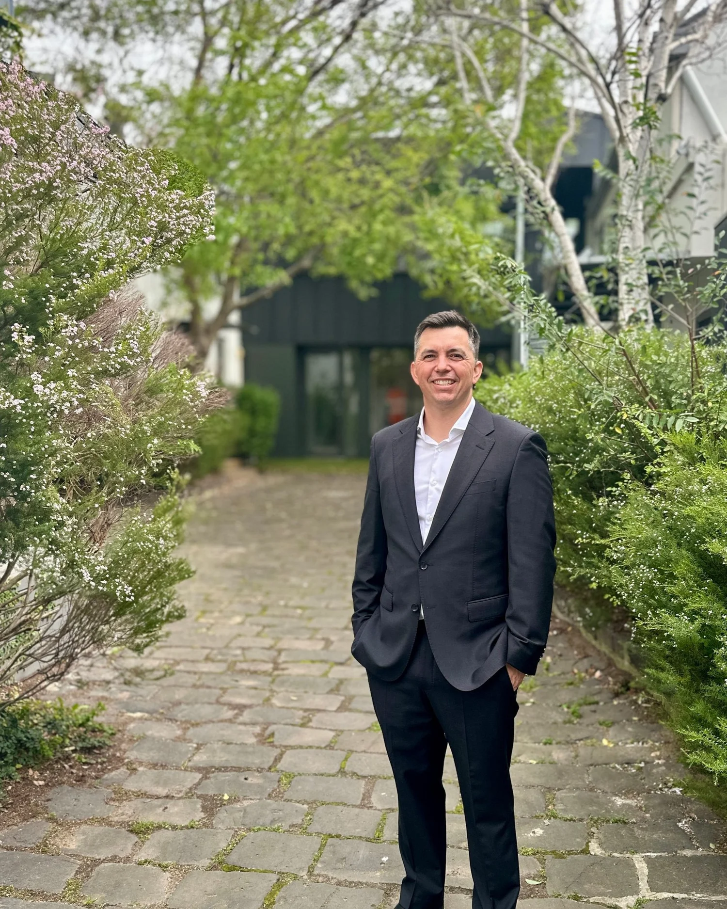 A profile photo of Andrew Humphries in a suit in a leafy outdoor setting