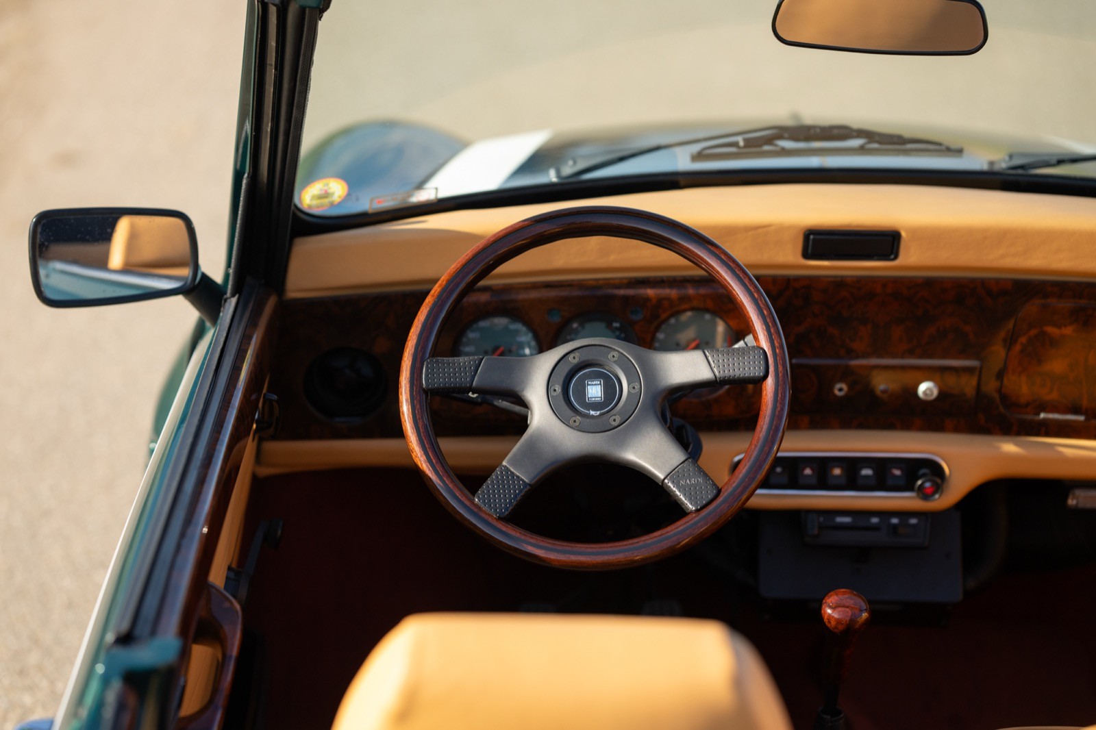 Interior view of a classic car showcasing the steering wheel, dashboard, and a leather seat.