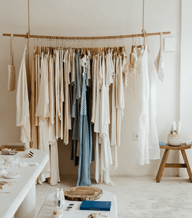 Neutral-toned clothing on a rack, with dried grass.