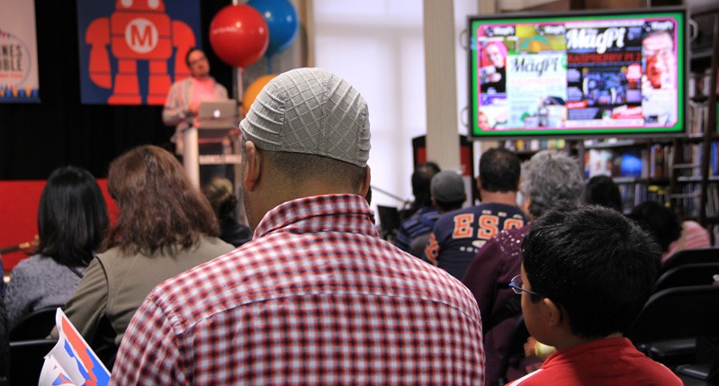 A photo of a group of people listening to a lecture and watching something on a tv screen.