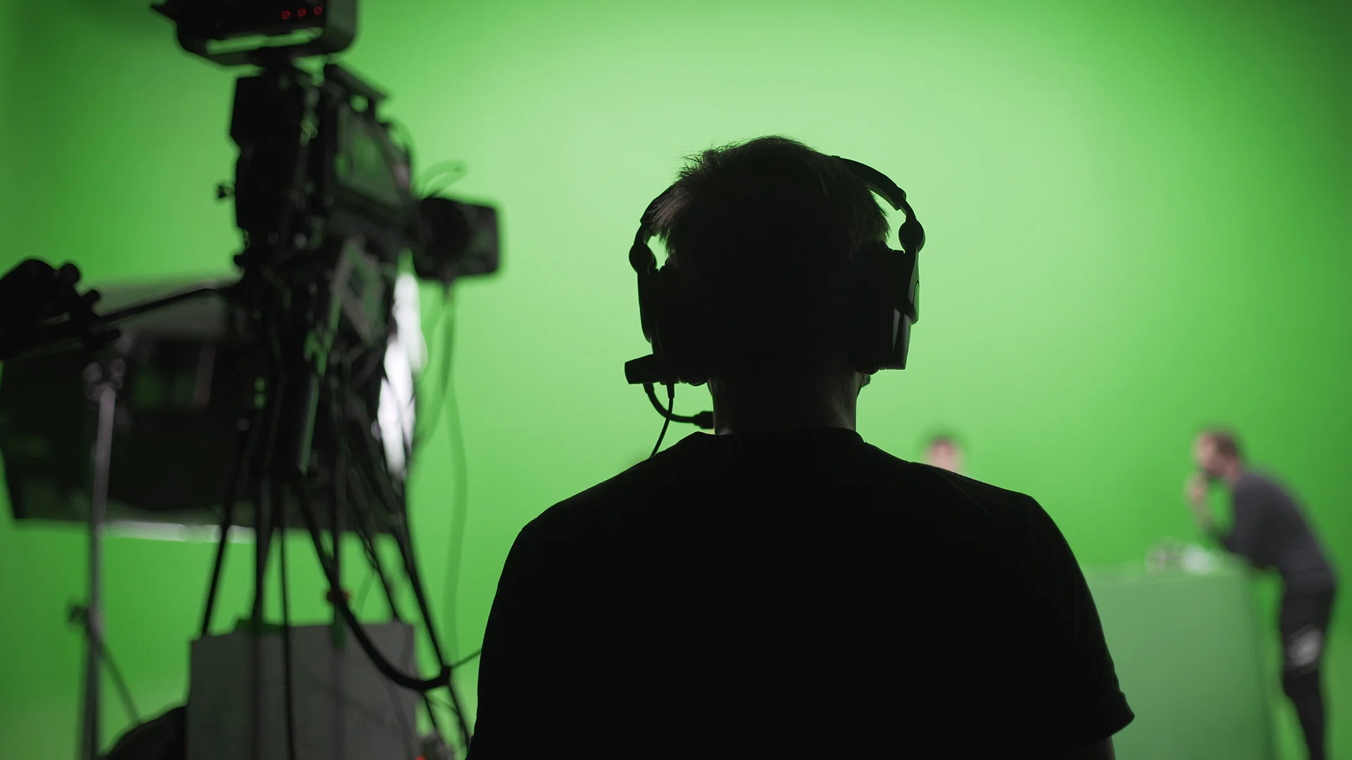 Broadcast technician monitoring a studio production during a green screen shoot.