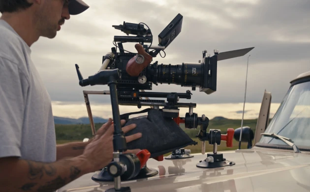 A cinema camera with a DZOFILM Arles zoom lens mounted on a vehicle roof for filming