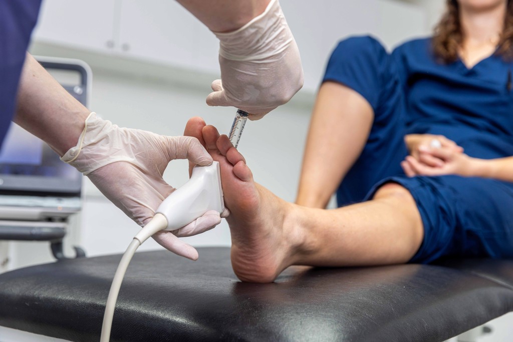 Image of a podiatrist using a handheld scanner working on a foot.