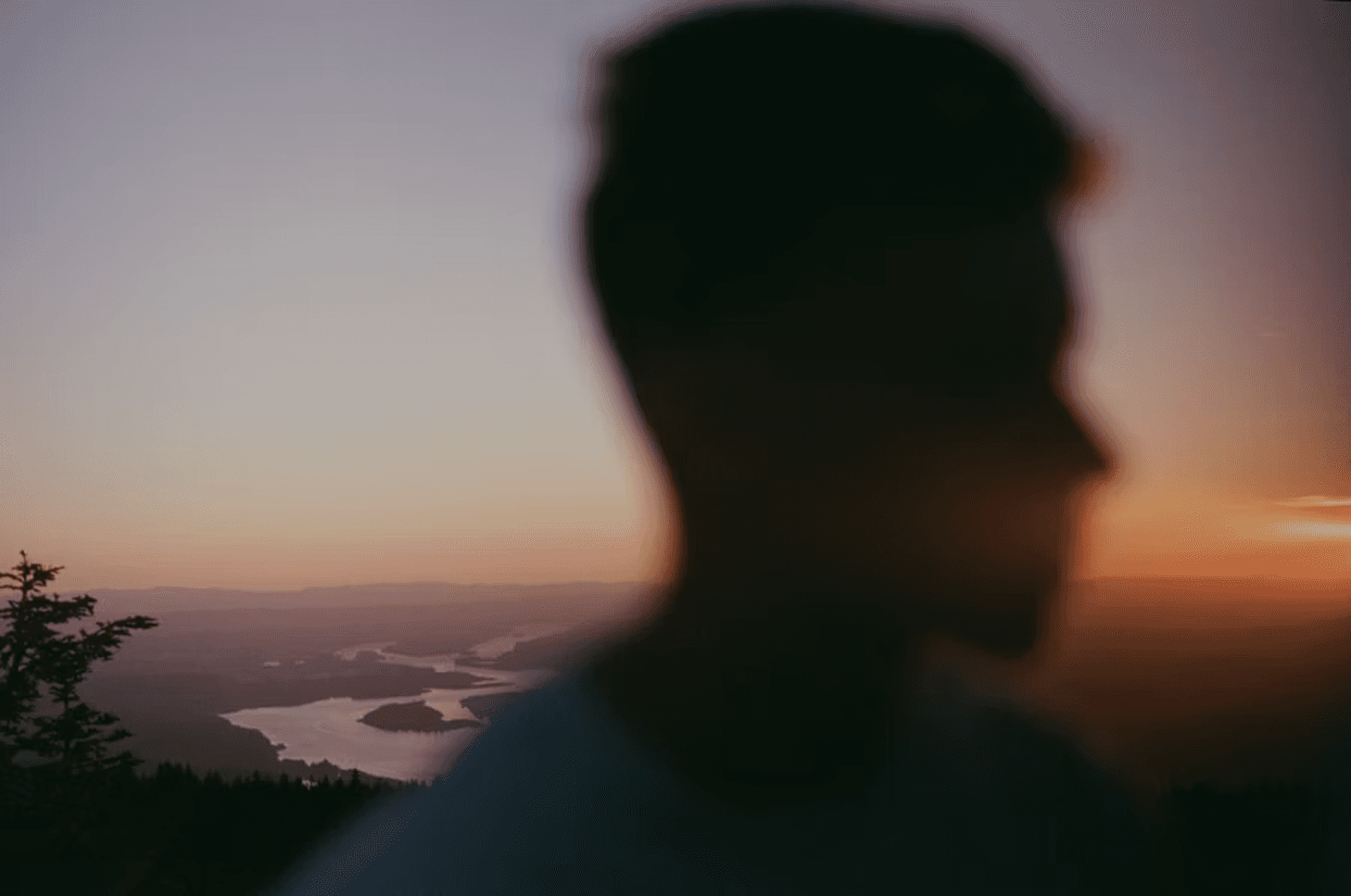 Out-of-focus silhouette of a person against a warm sunset sky.