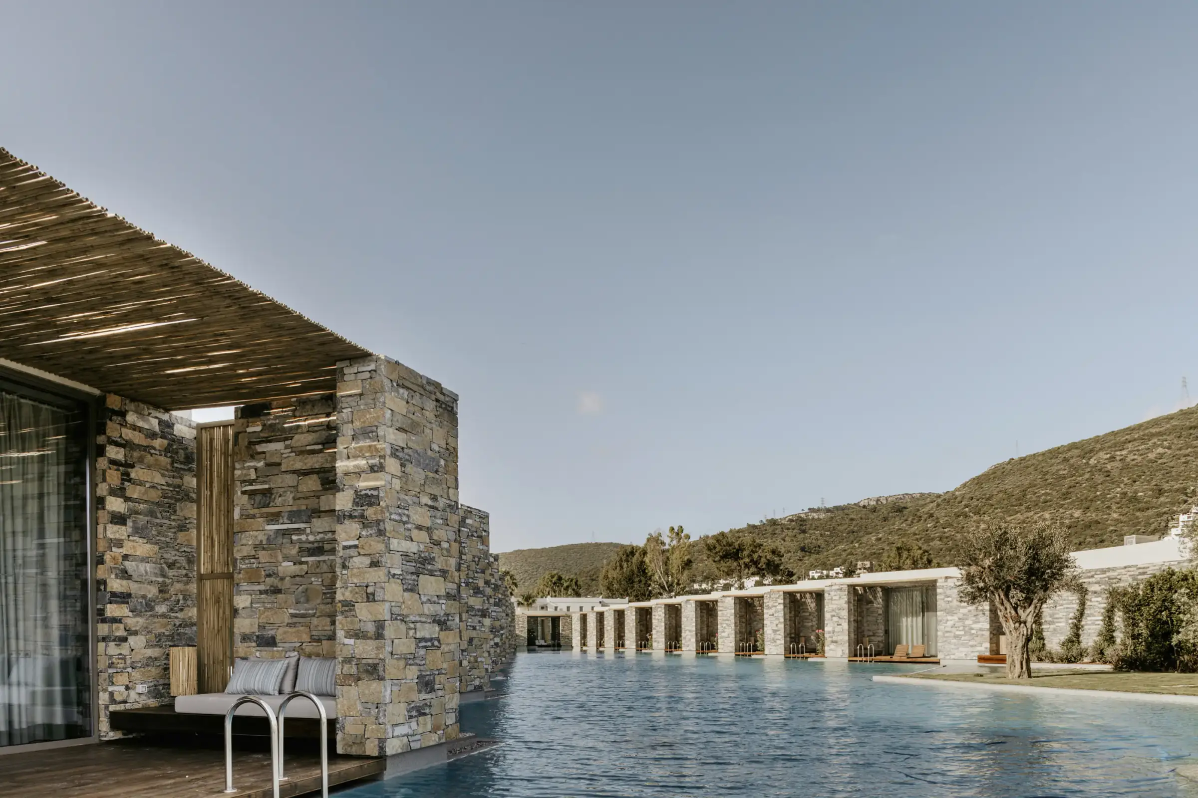 Room terrace with reed canopy and rooms extending along the pool