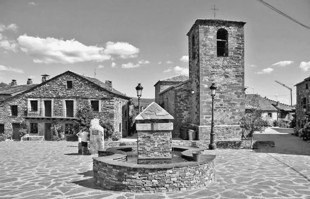 Four diverse professionals collaboratively working on a laptop, with one person pointing at the screen while others observe.