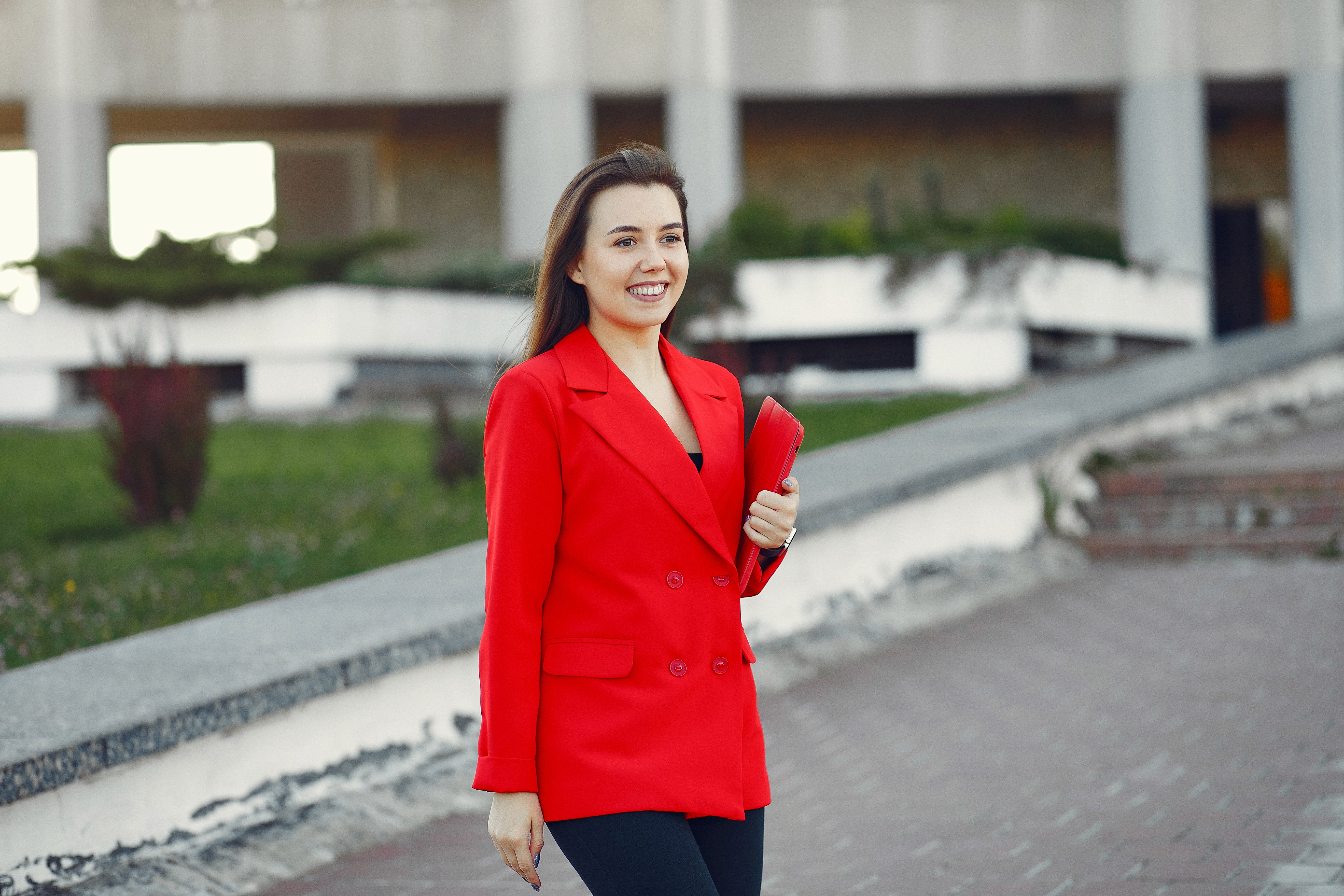 Businesswoman in a red suit holding a folder outdoors