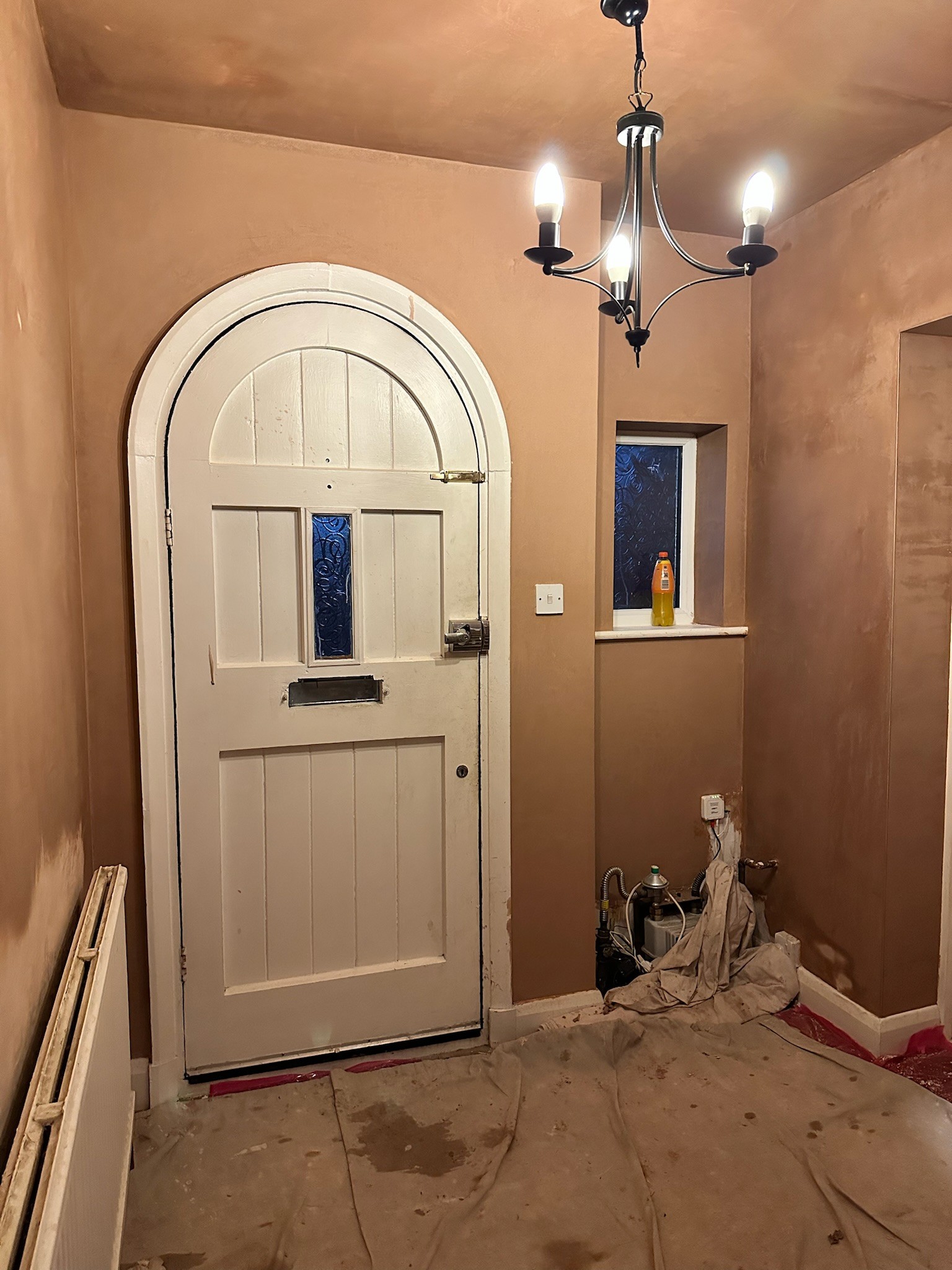 Fully plastered hallway with arched door.