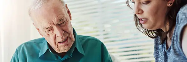 Elderly man and caregiver reading together