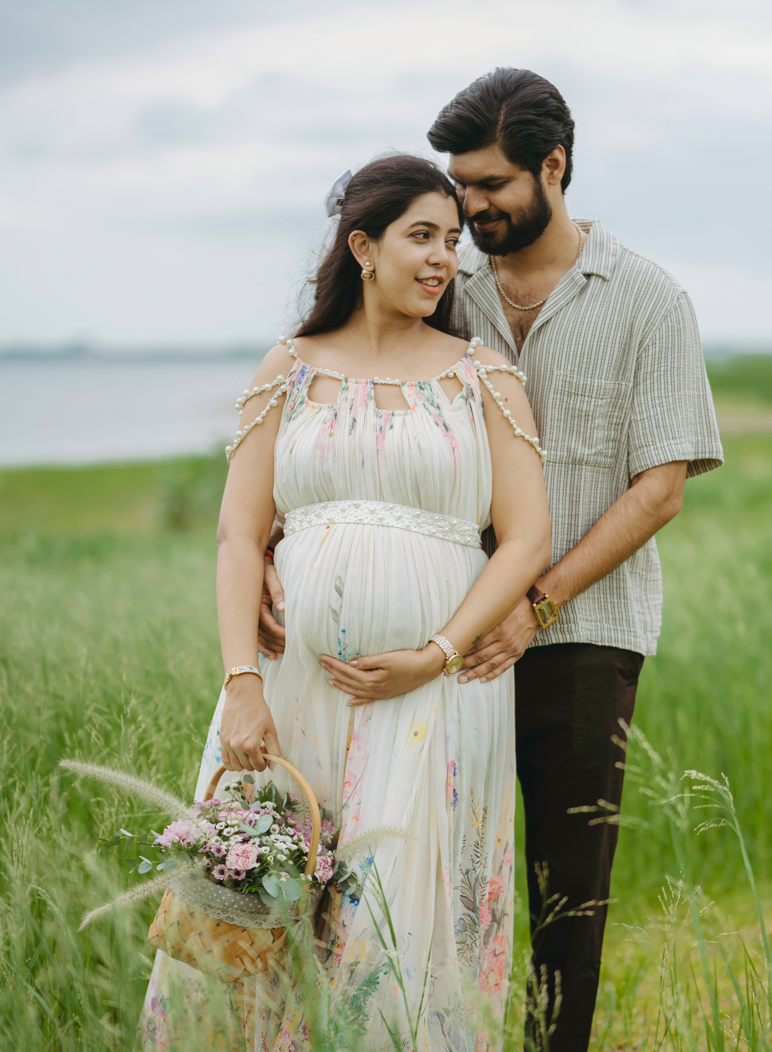 Maternity photoshoot of couple in traditional attire against a floral backdrop, captured by Wow Makers in Hyderabad, India.