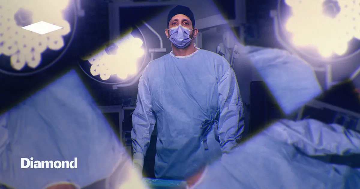 Surgeon in a mask and scrubs standing under operating room lights