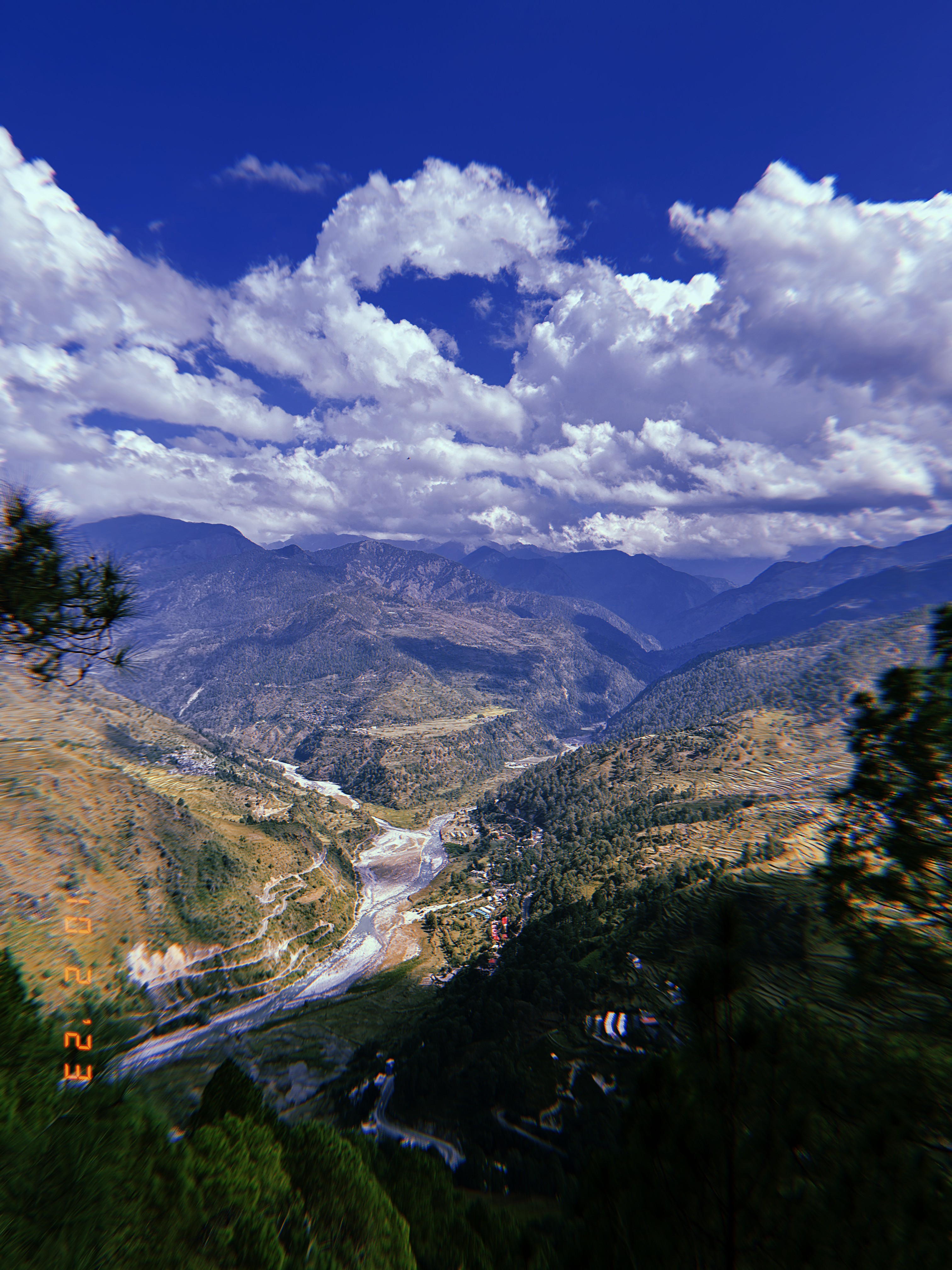 Mountain valley, river and road beneath a cloud-filled sky