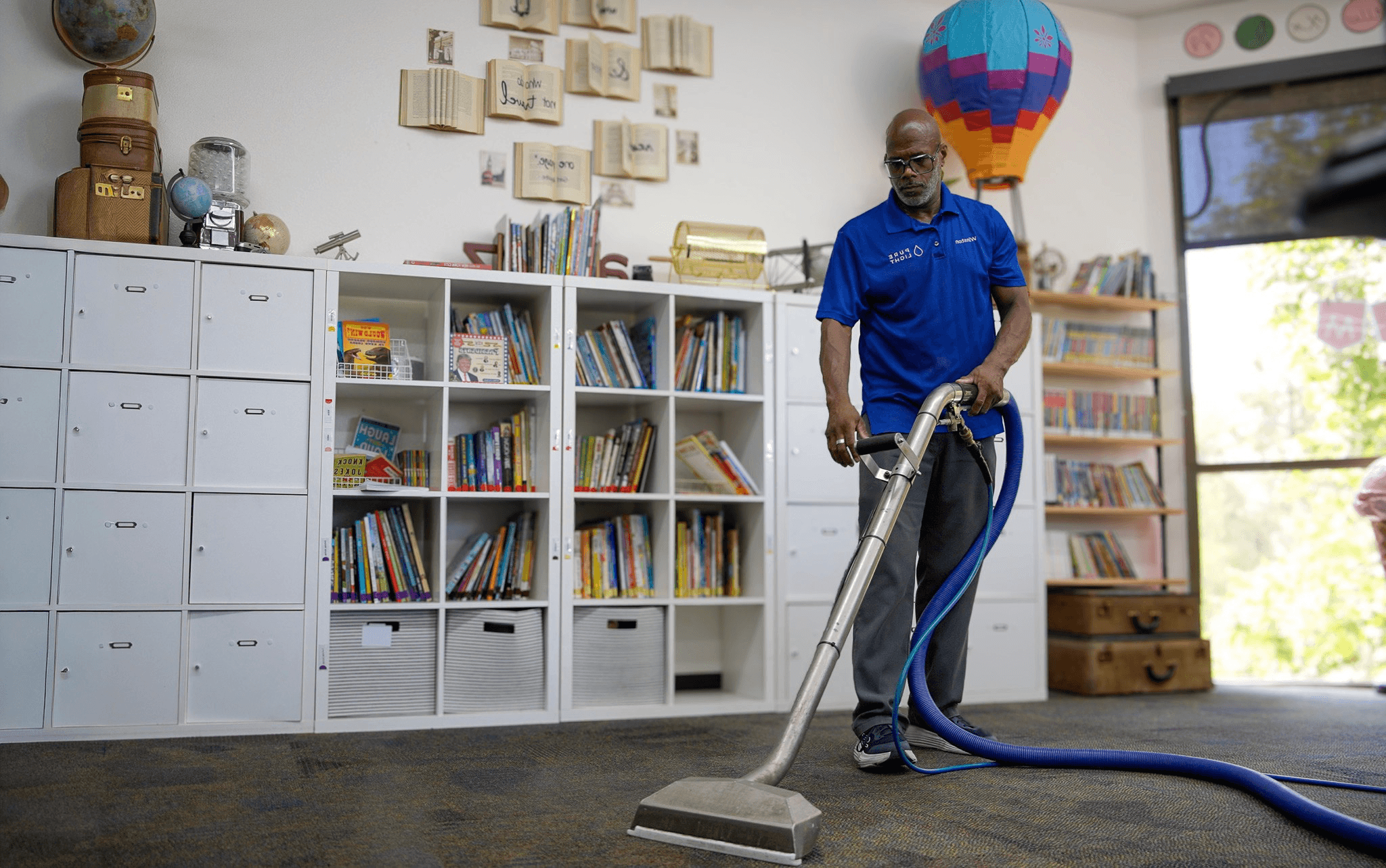 Pure Light technician steam cleaning carpet in a modern office hallway with glass-walled meeting rooms