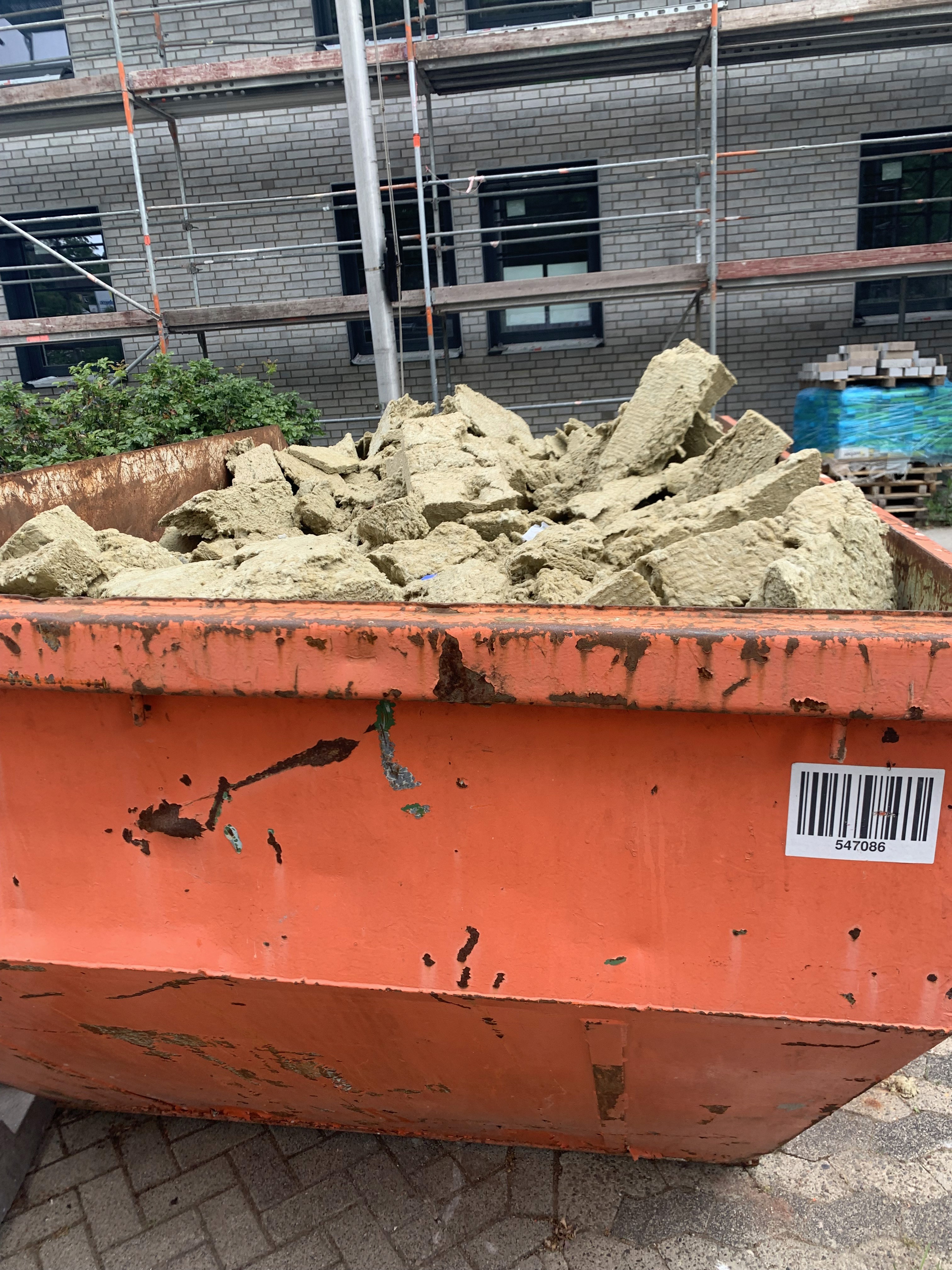 Orangener voller Bauschuttcontainer.