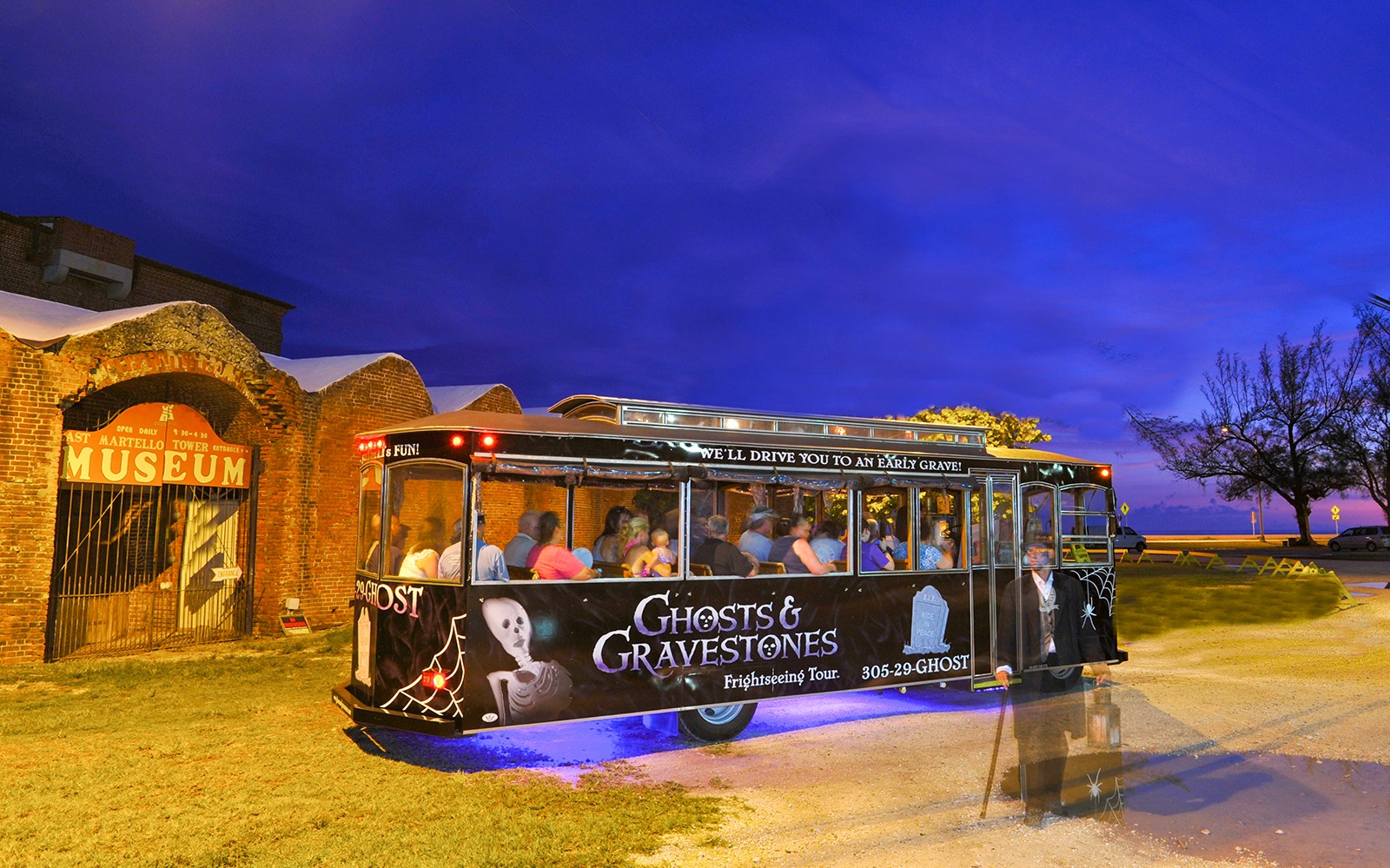 Boston Ghosts & Gravestones tour trolley at night near a historic museum entrance.