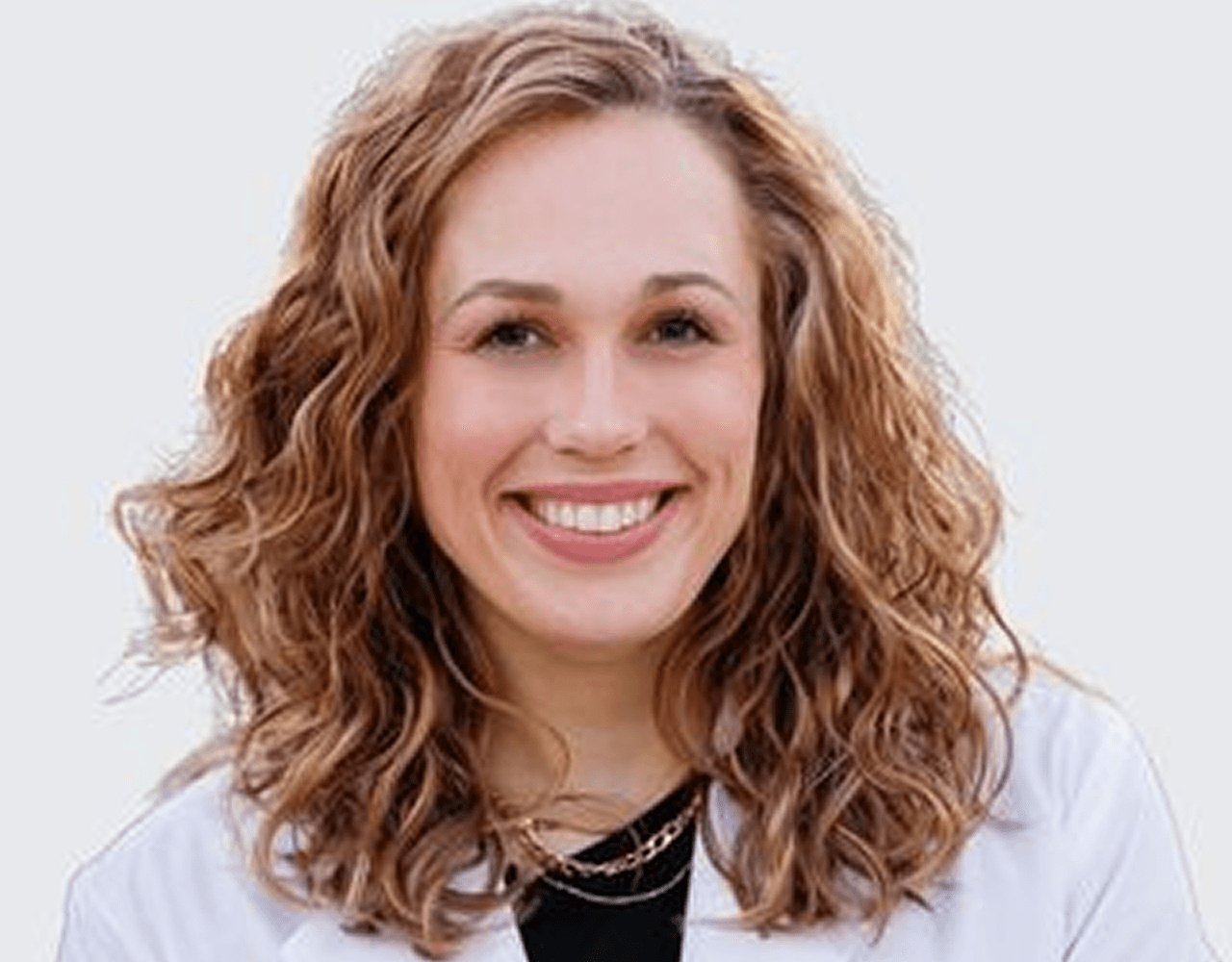 A woman in a white coat is posing for a picture