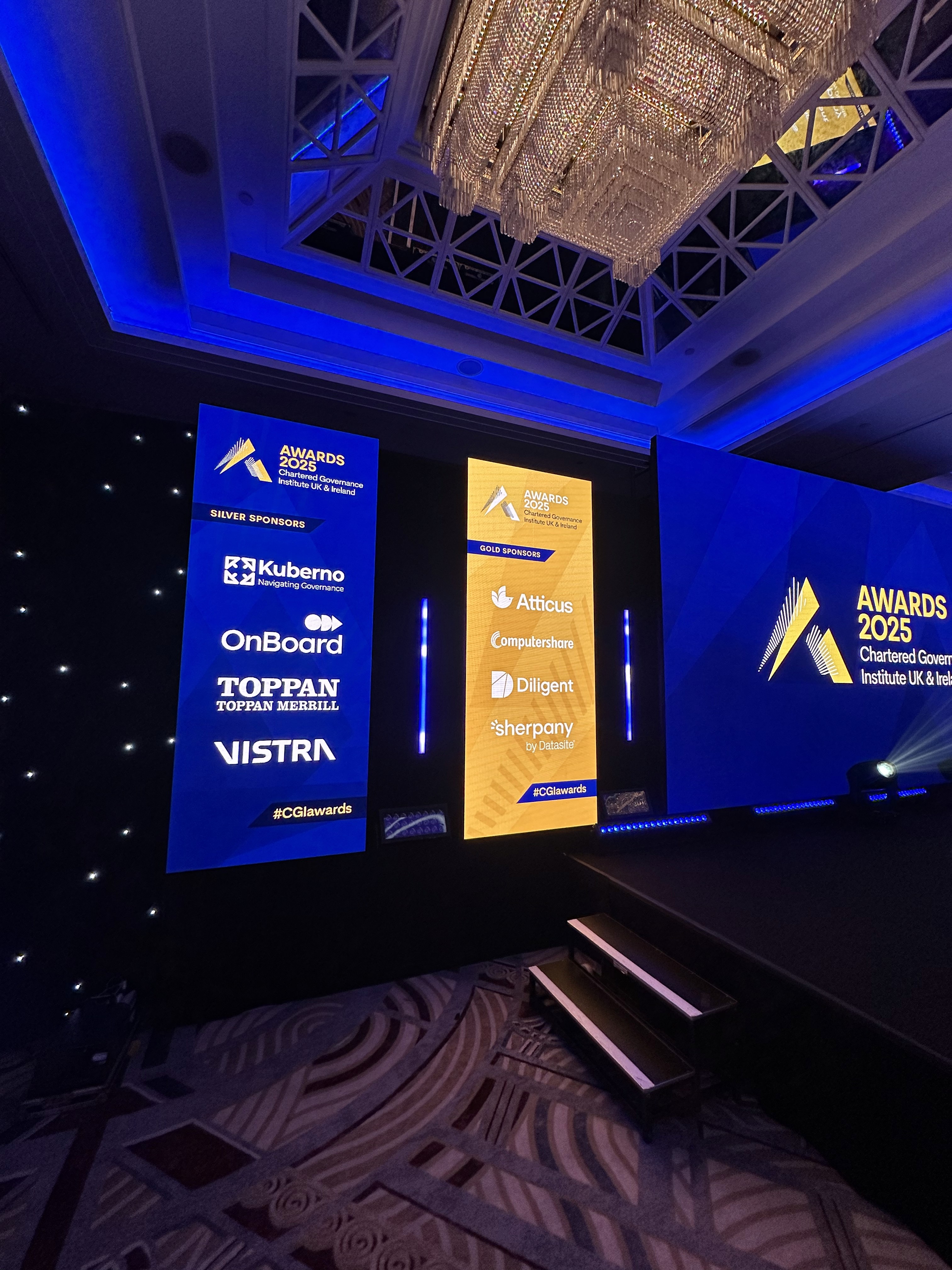 Vertical LED totems displaying CGI Awards gold and silver sponsors beside a black starcloth backdrop.