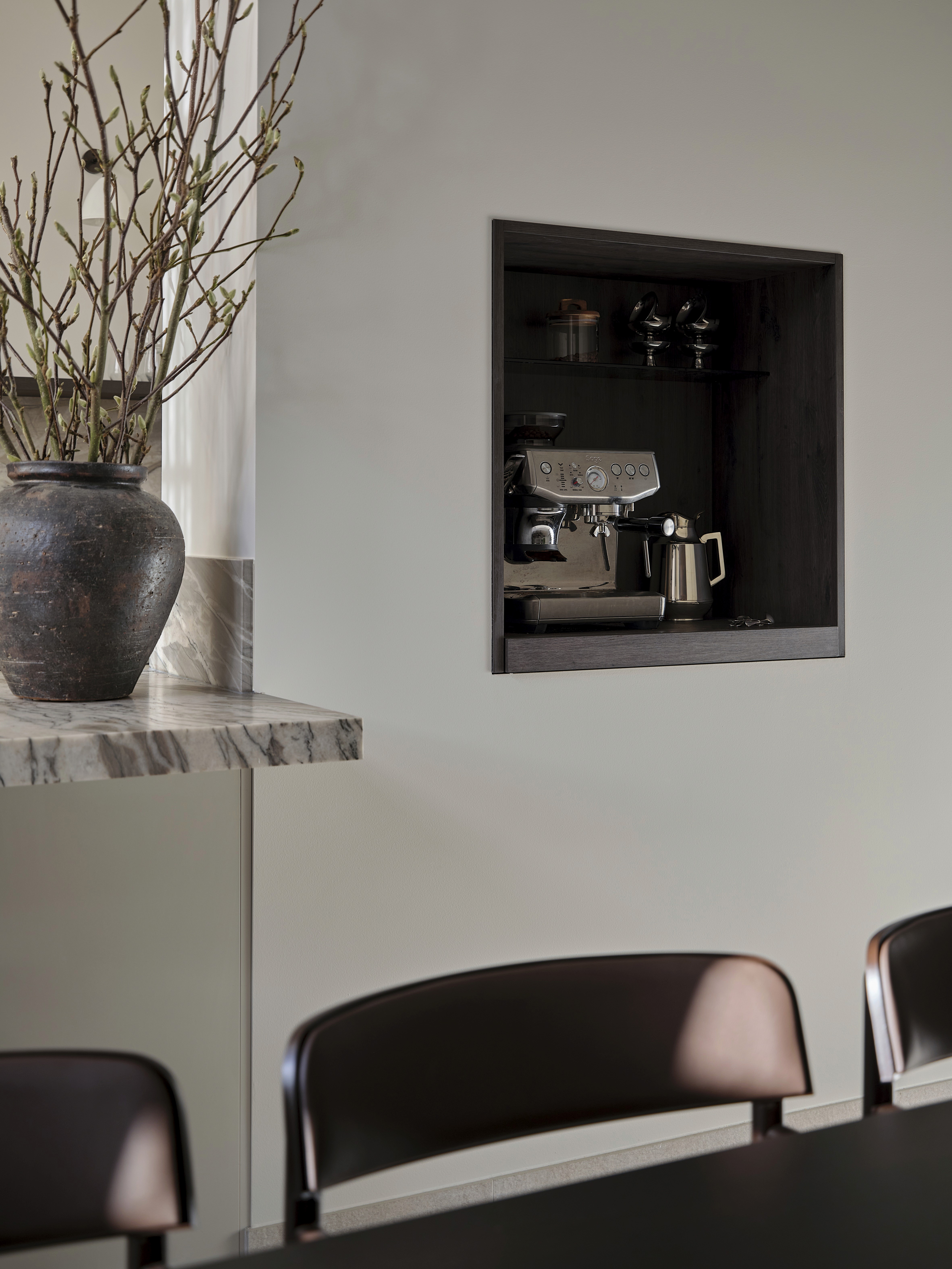 Built-in coffee station niche with professional espresso machine, quartzite countertop, and dark timber shelving