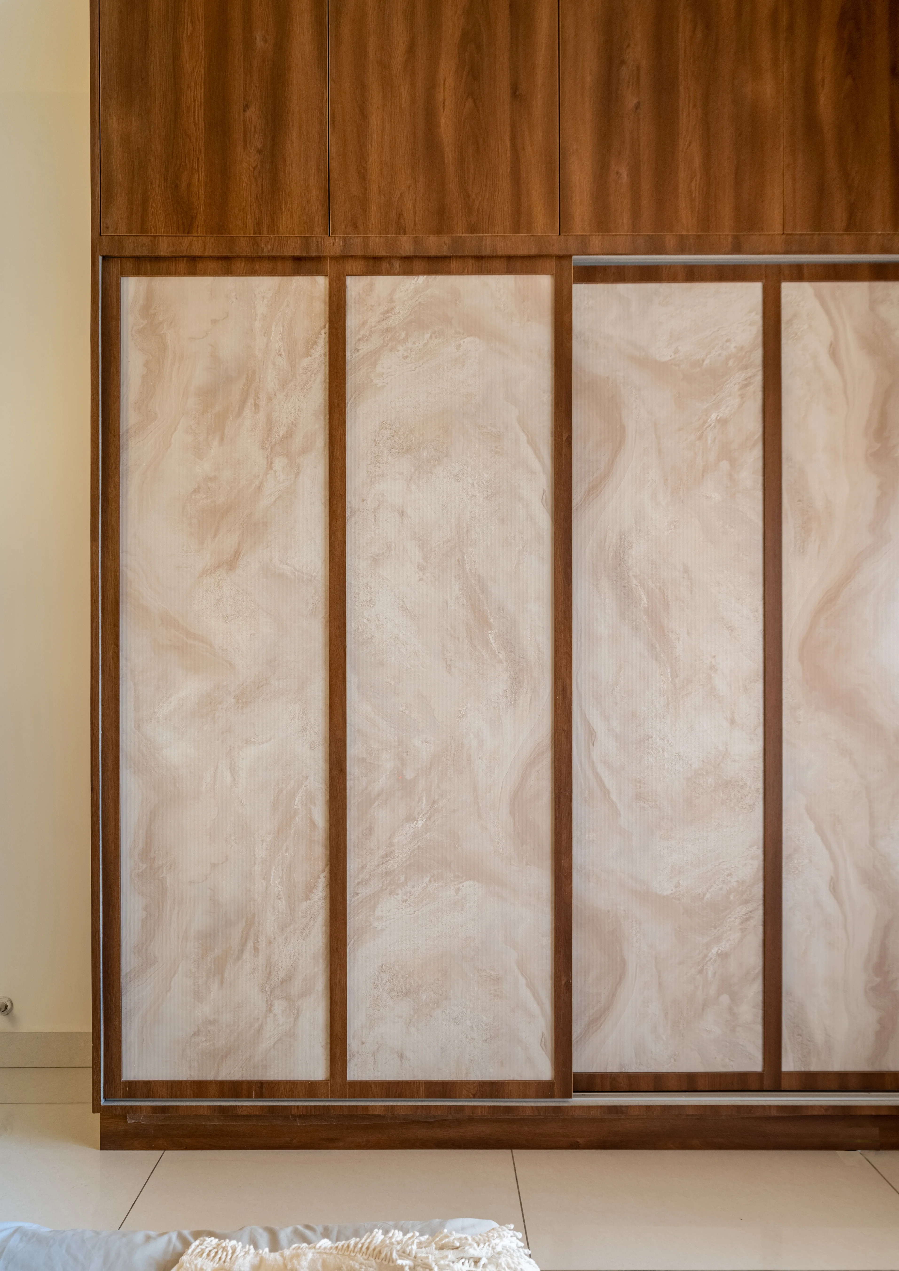 A wardrobe with sliding doors featuring a combination of wood and marble-fluted panels.