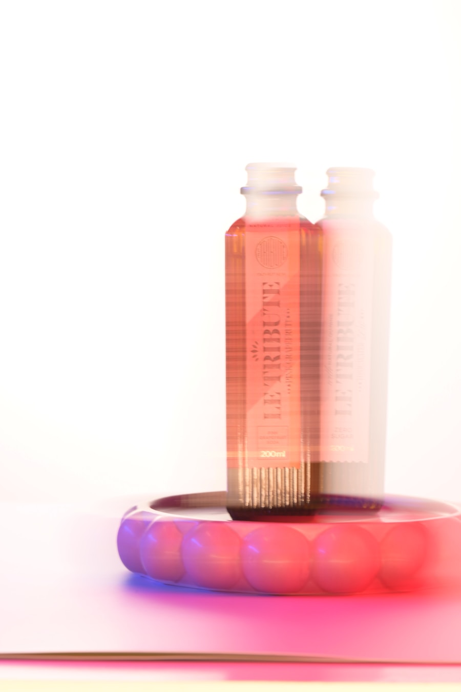 Skincare serum bottles in a luminous pink studio setting
