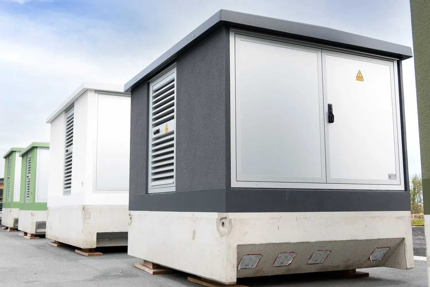 Mehrere weiße und anthrazitfarbene Energiecontainer mit Lüftungsgittern.