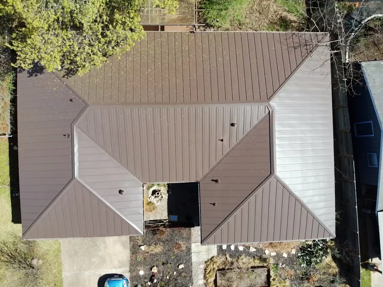 Brown standing seam metal panels follow the hips and valleys around a recessed entry on an Austin home.