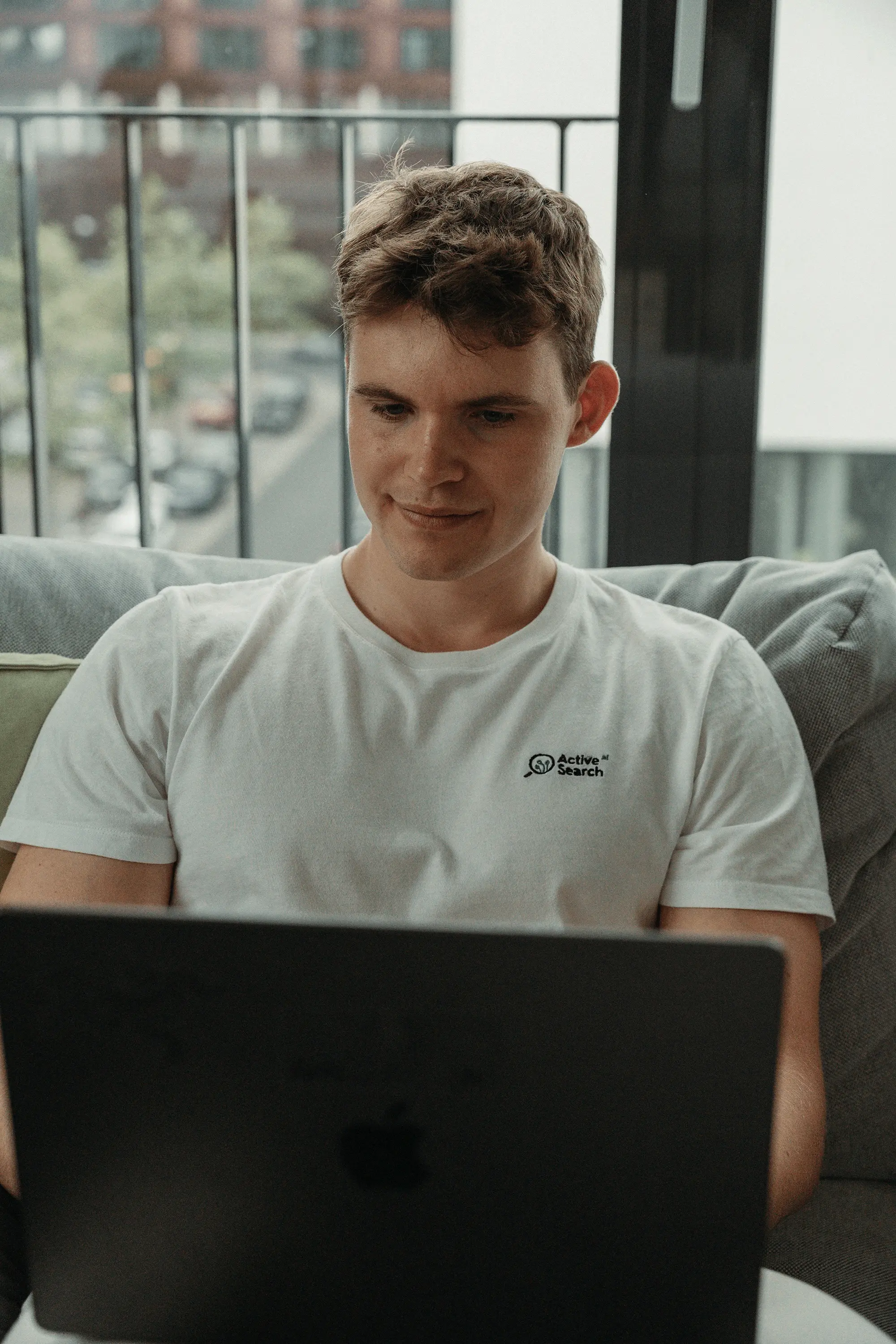 Man with short dark hair wearing a light green shirt, sitting near a window in soft light