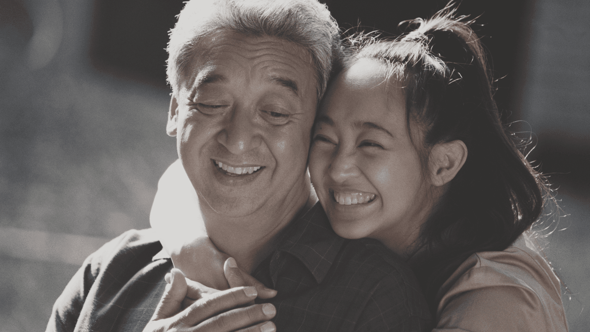 A daughter is hugging a dad. Both smiling