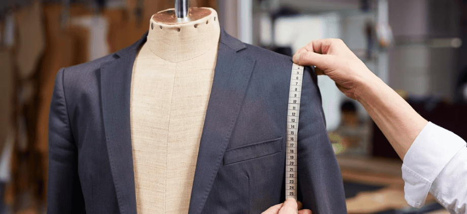 a tailor measureing the arm length on a suit jacket
