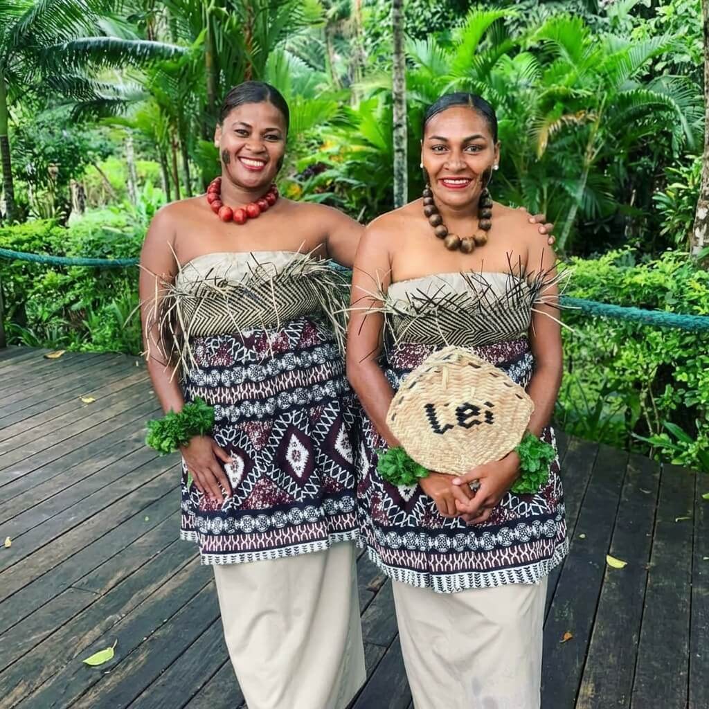 2 Fijian women in traditional costume smiling joyfully