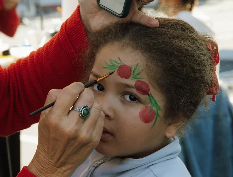A volunteer does face-painting for kids