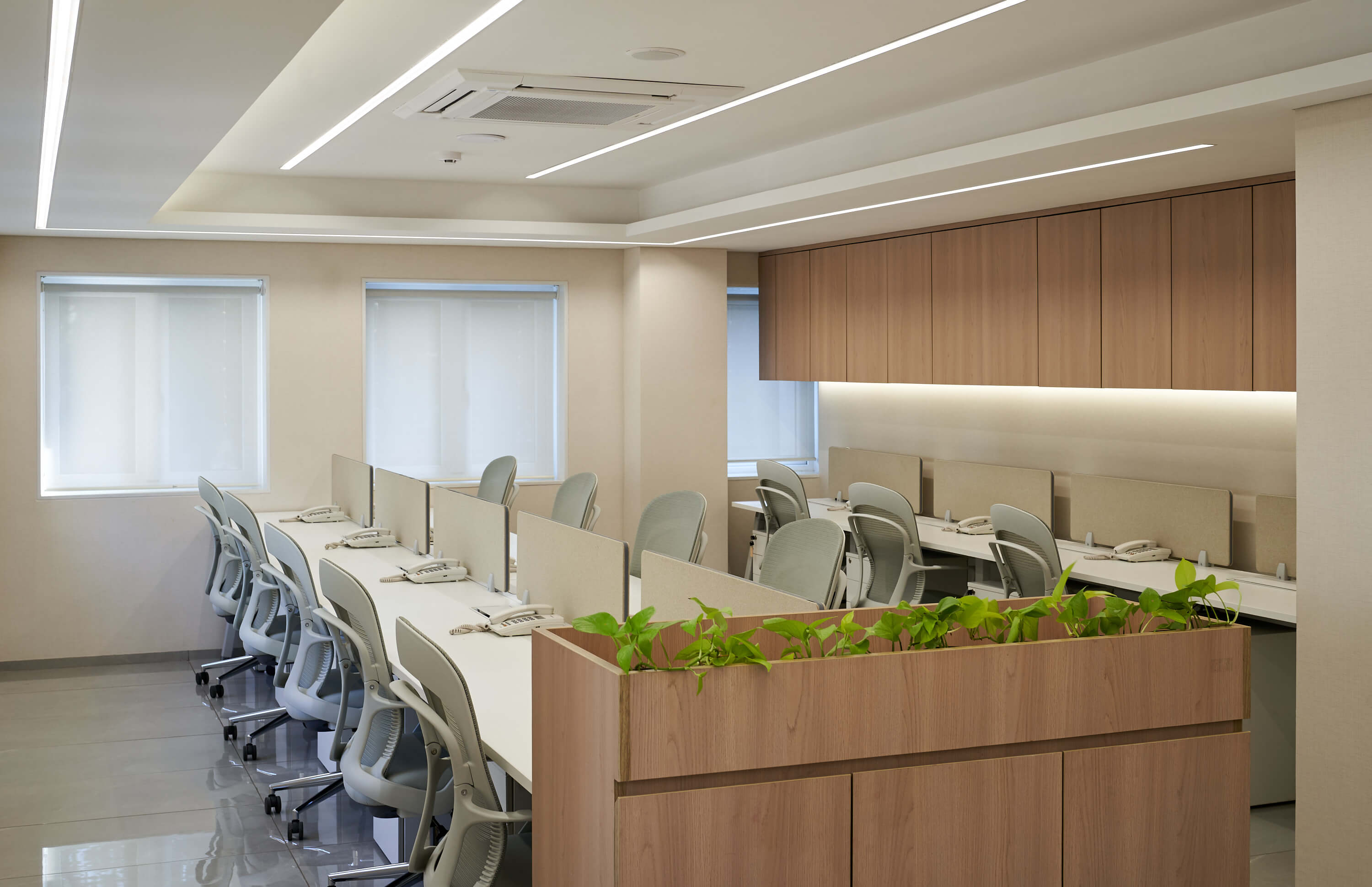 Open-plan office workspace with white desks, ergonomic chairs, and wood storage units.