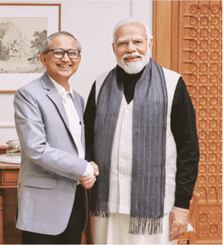 A woman with red hair and a black sleeveless top smiling confidently in a bright, modern indoor setting.