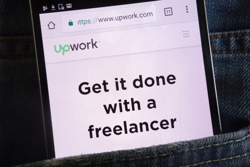 Upwork website displayed on smartphone hidden in jeans pocket
