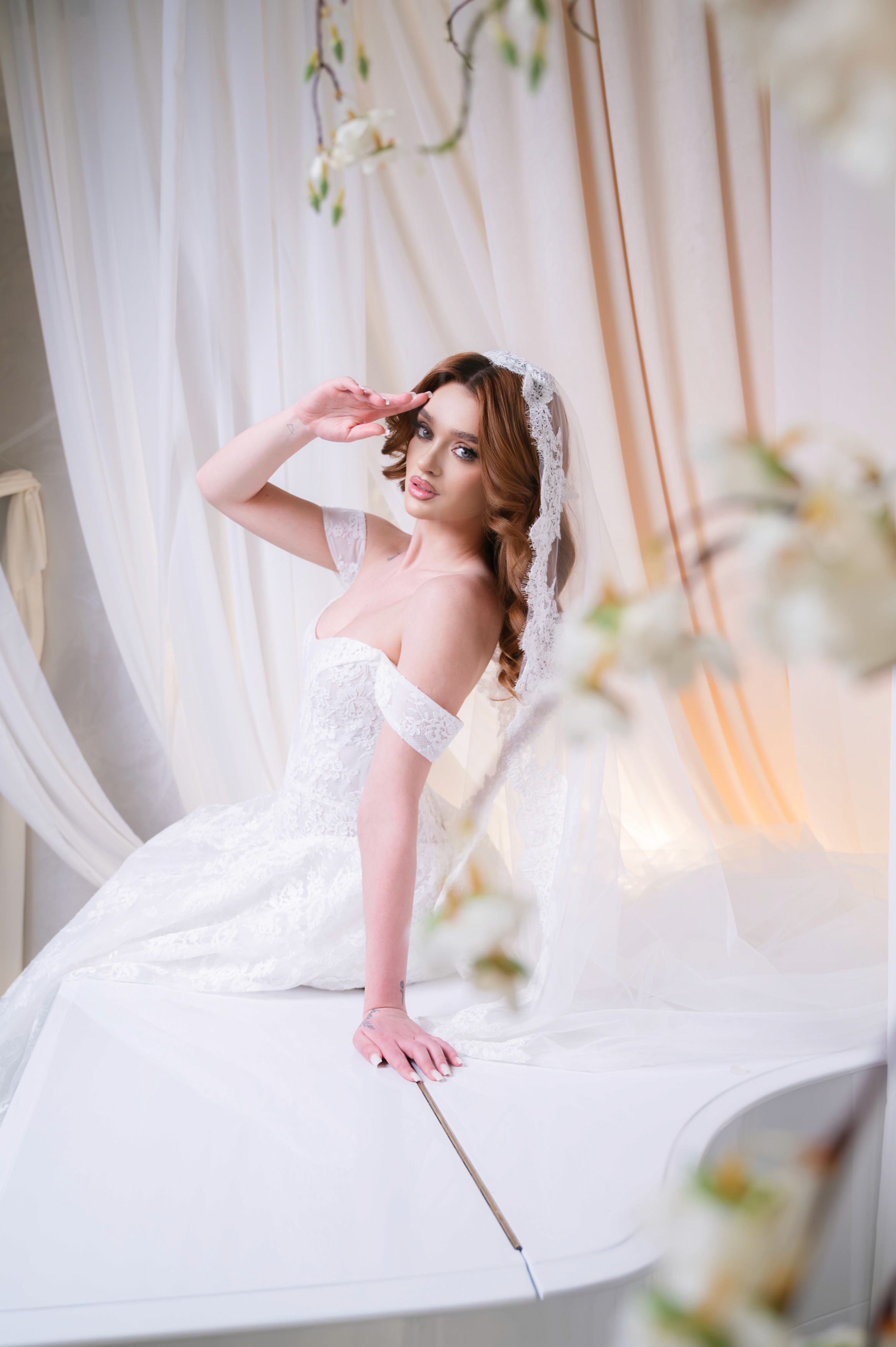 Mireasă fotografiată întinsă pe un pian alb într-un decor elegant, fotografie de nuntă în București