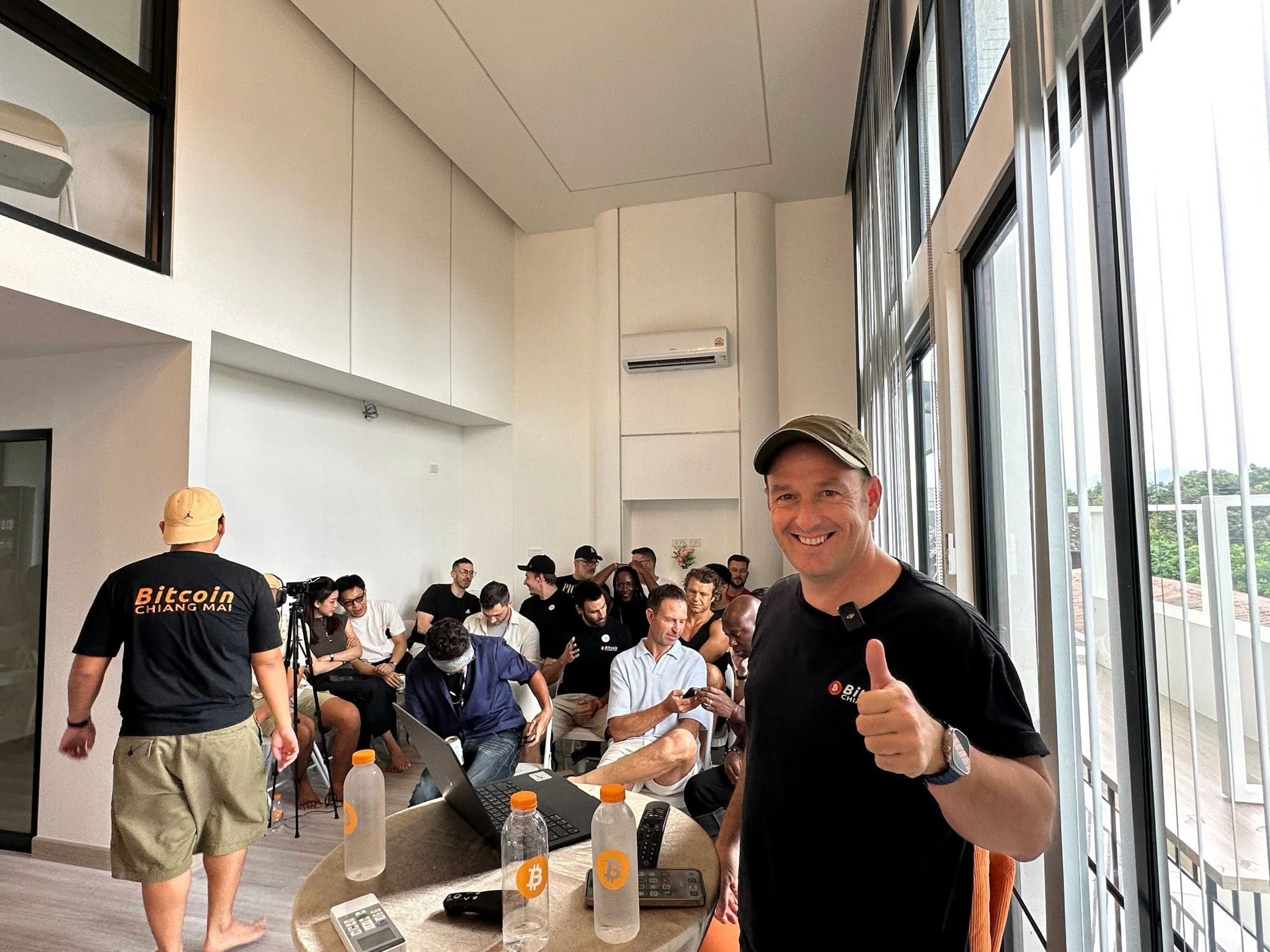 Jimmy Kostro giving a thumbs-up at a Bitcoin Chiang Mai event with international guests including Fedi CEO Obi Nwosu and author Jeff Booth