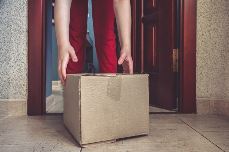 Person picking up a delivered parcel at the doorstep
