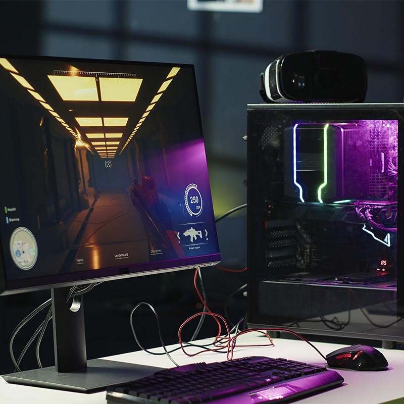 Monitor exibindo jogo em primeira pessoa conectado a gabinete gamer iluminado, representando a realização de montar seu setup dos sonhos com o consórcio Klubi.