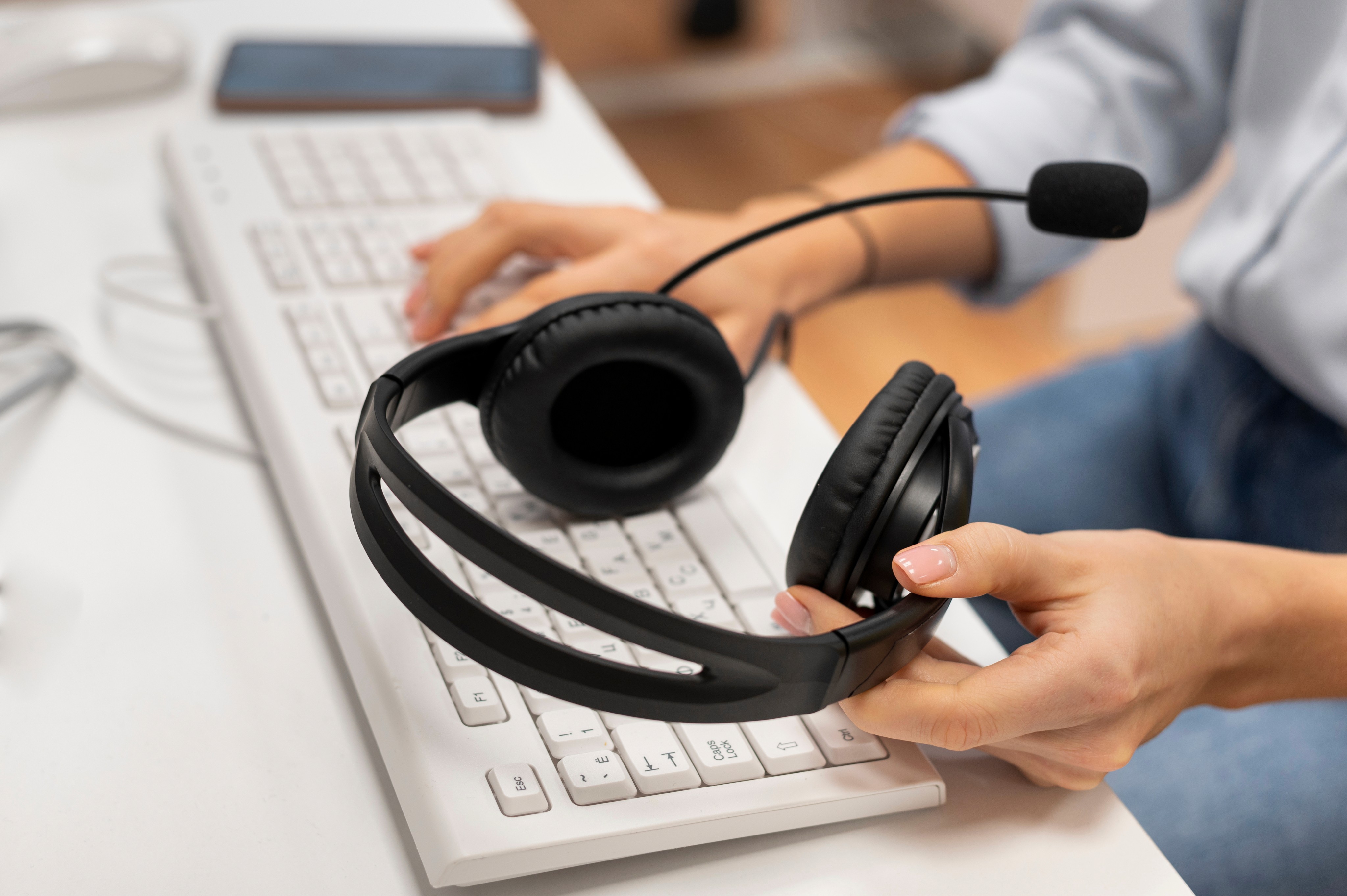 Hands of a professional with a headset working at a desk.