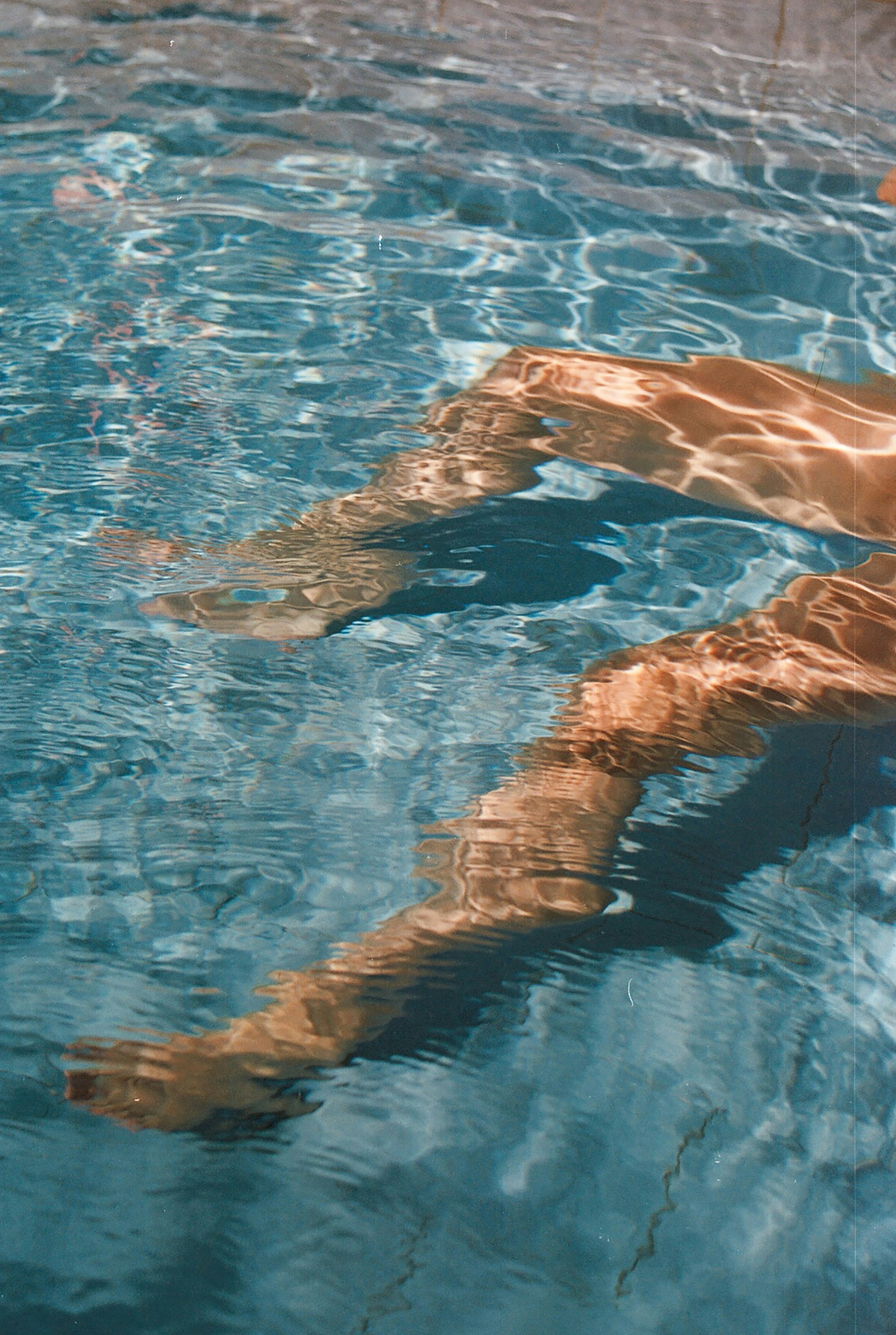 A man swimming in a pool with no shirt on