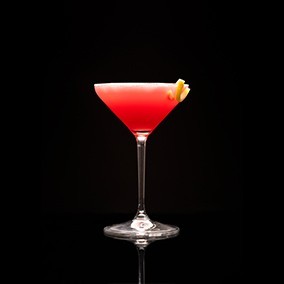 A closeup of a Pomegranate Martini drink against a dark background.