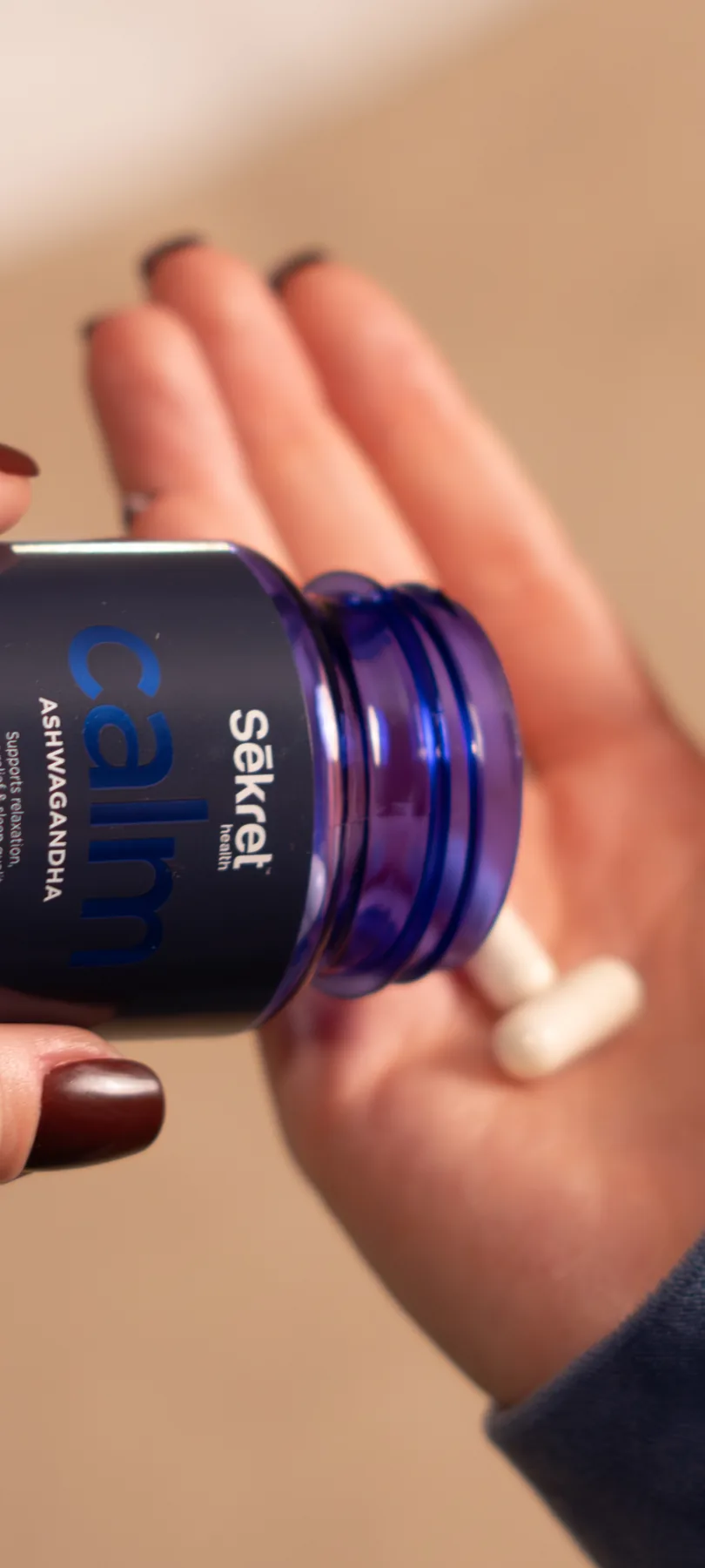 A capsule tipped from a bottle of Sēkret Calm into an open hand at home