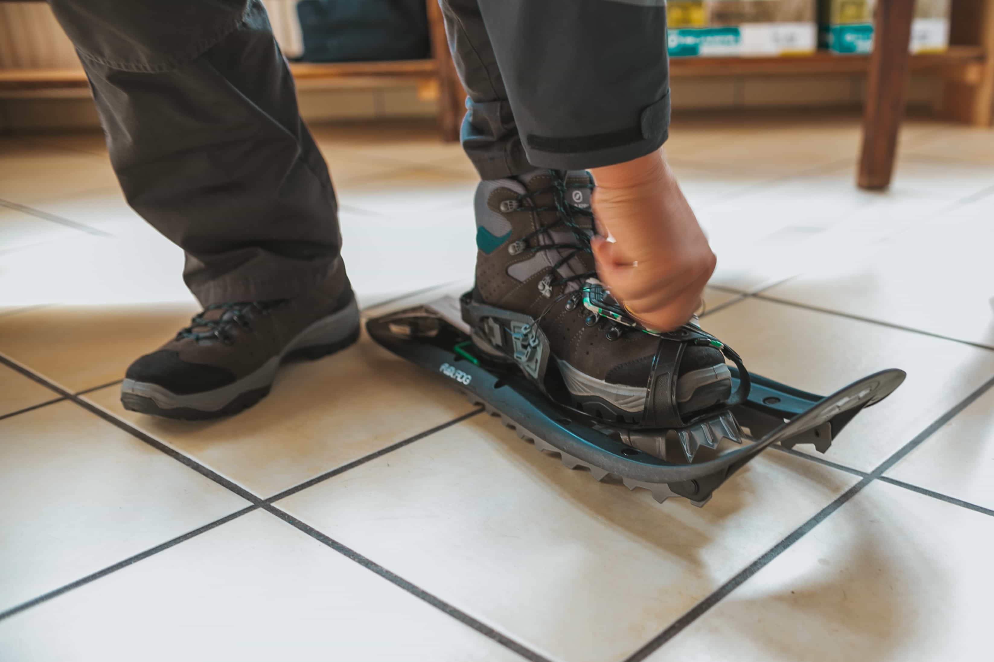 A person puts on snowshoes from Tubbs