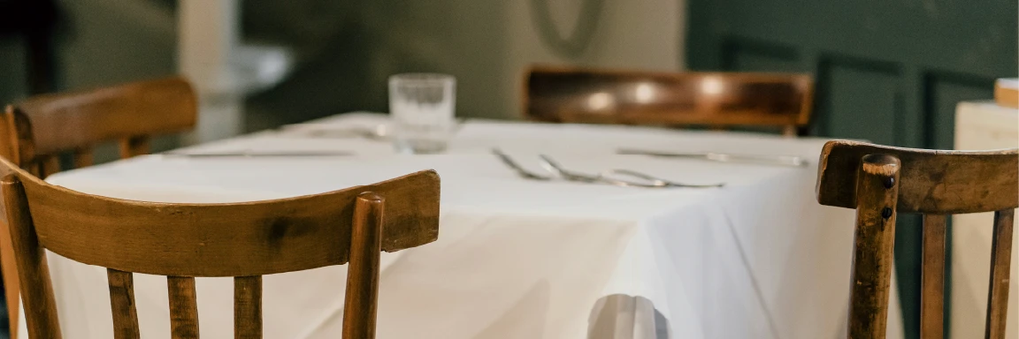 A restaurant patio sits under large, leafy trees.