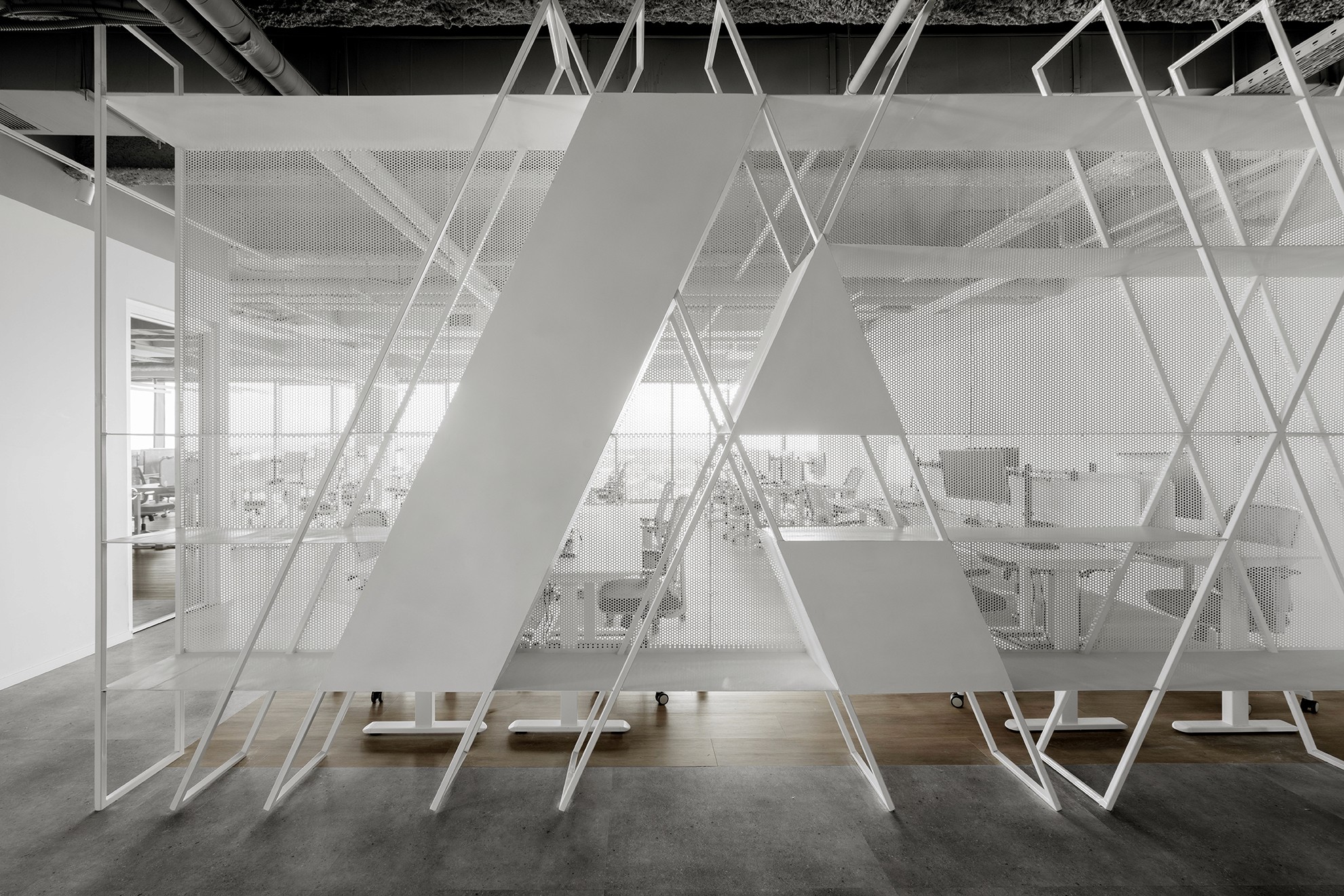 אלמנט אדריכלי בייצור אישי: מחיצת רשת מתכת (Expanded Mesh) לבנה בדיגום גאומטרי, המשלבת את לוגו החברה ("A") ושומרת על שקיפות