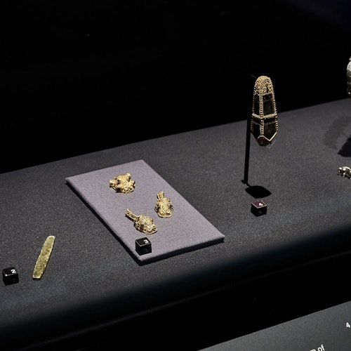 Display case with ancient artifacts, including gold ornaments, a decorated pendant, and a small knife, each on individual mounts.