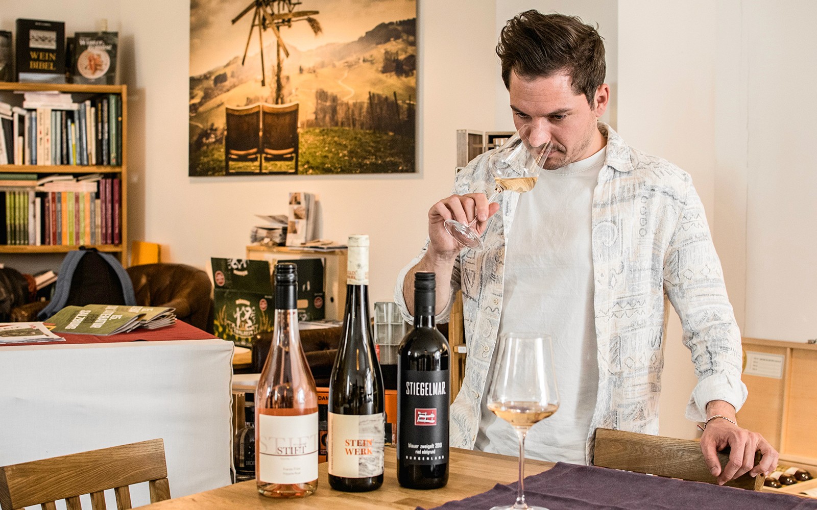 Man tasting wine in a cozy wine bar with bottles on the table.
